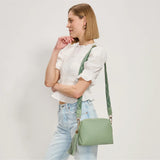 Green textured handbag with a green black and white striped strap model 