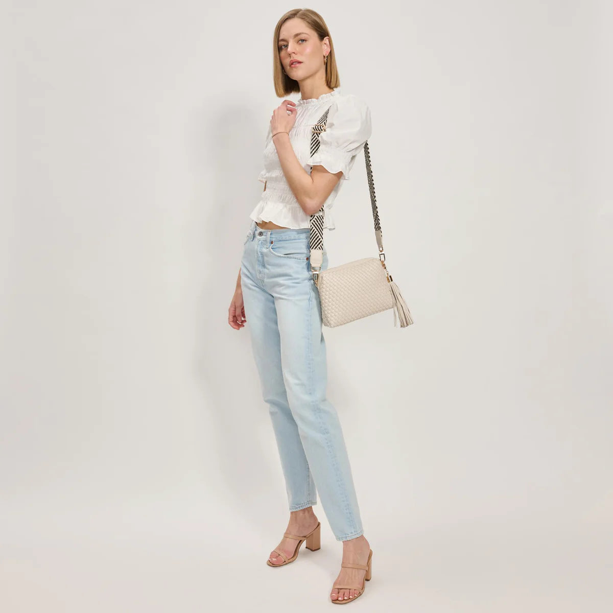 White textured handbag with a black and white striped strap model 3