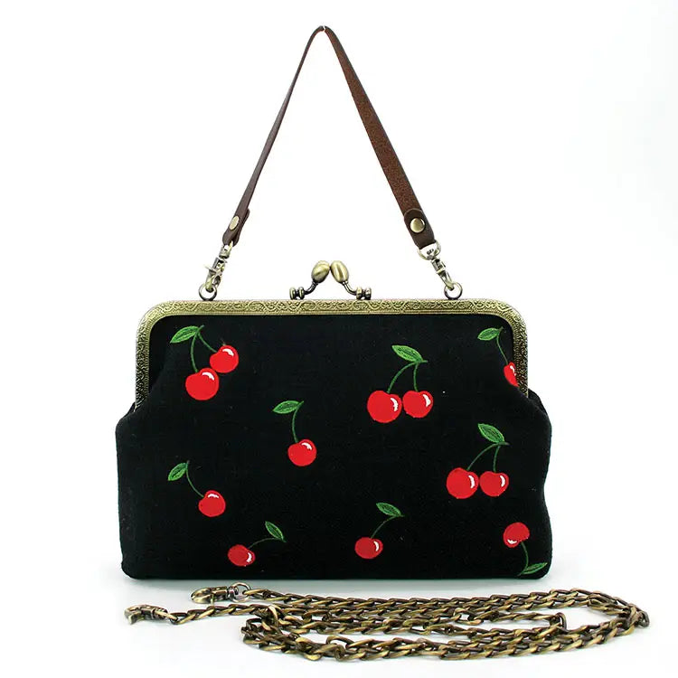 Black handbag with red cherry design close-up