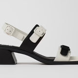 Black and white modern sandal with a block heel and buckle straps close up