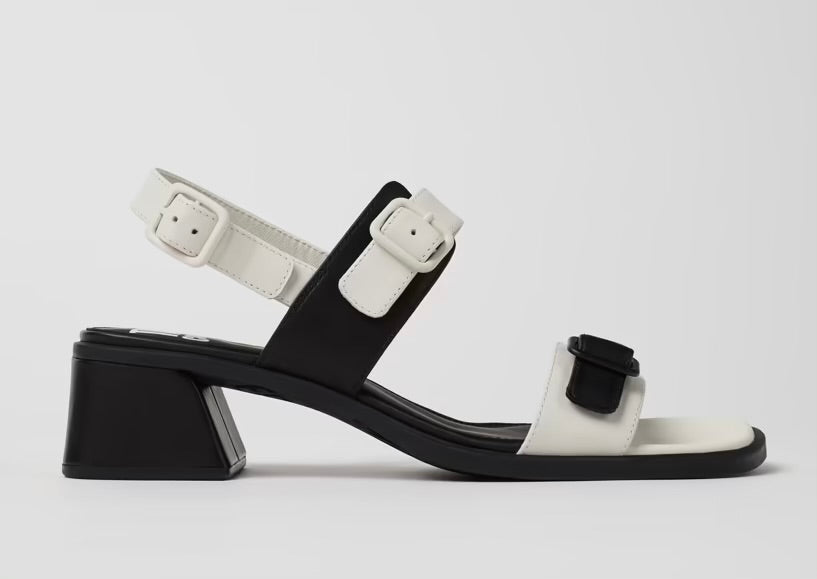 Black and white modern sandal with a block heel and buckle straps close up