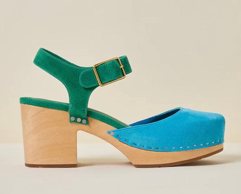 Green and blue suede shoe with golden buckle and wooden heel on a beige background