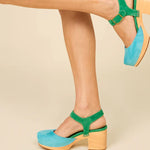 Green and blue suede shoe with golden buckle and wooden heel close up on pair on model