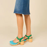 Green and blue suede shoe with golden buckle and wooden heel pair on model standing 