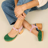 Green and blue suede clog shoe with pink strap with gold strap, and wooden sole pair on model