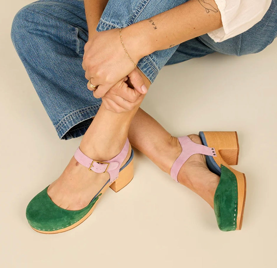 Green and blue suede clog shoe with pink strap with gold strap, and wooden sole pair on model