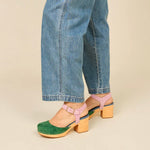 Green and blue suede clog shoe with pink strap with gold strap, and wooden sole pair on model standing