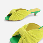 Yellow pleated kitten pen back sandal with a green heel close up on front