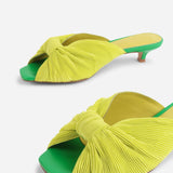 Yellow pleated kitten pen back sandal with a green heel close up on front