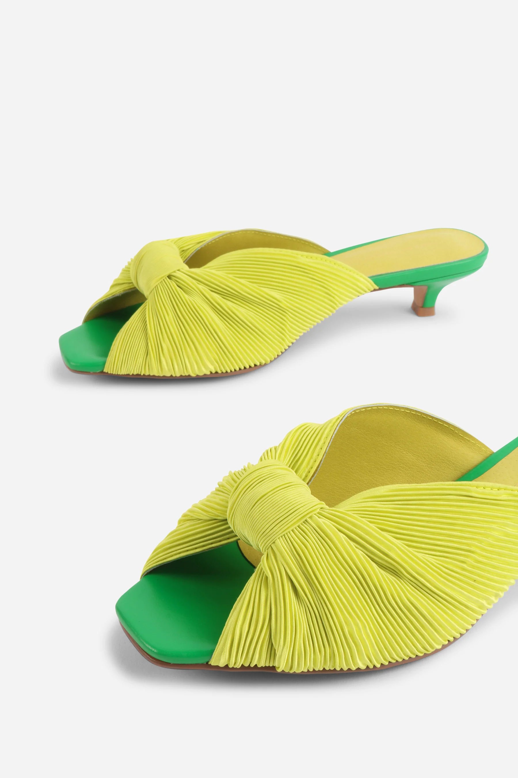 Yellow pleated kitten pen back sandal with a green heel close up on front