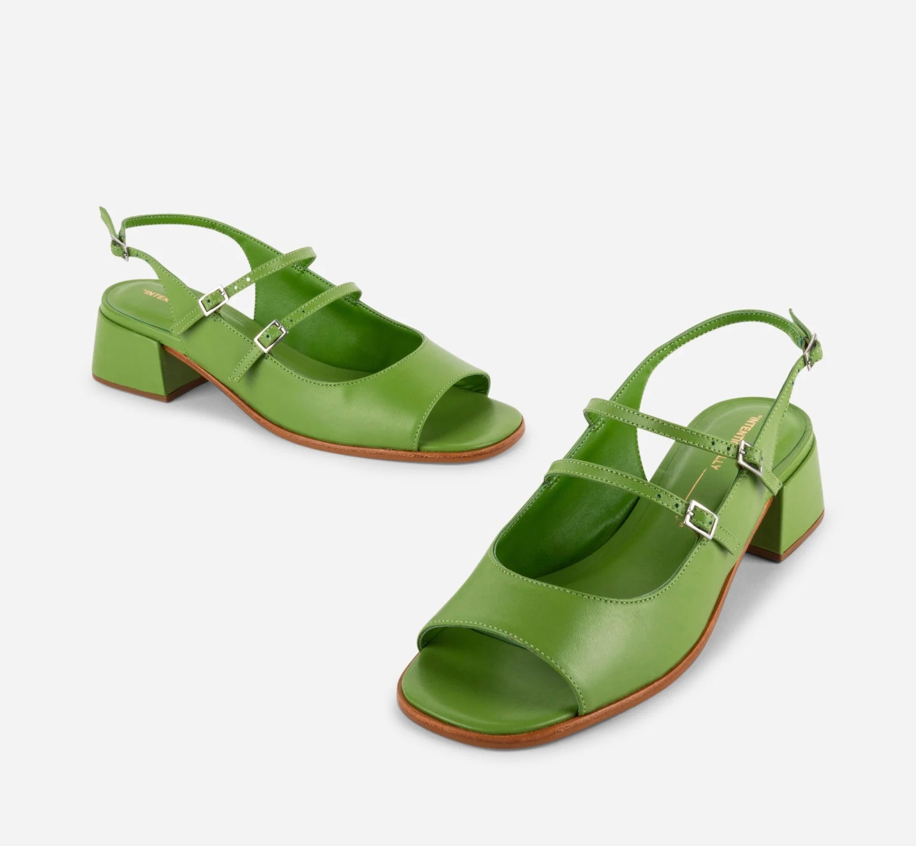 Green high-heeled shoes with open toes and thin straps on a white background