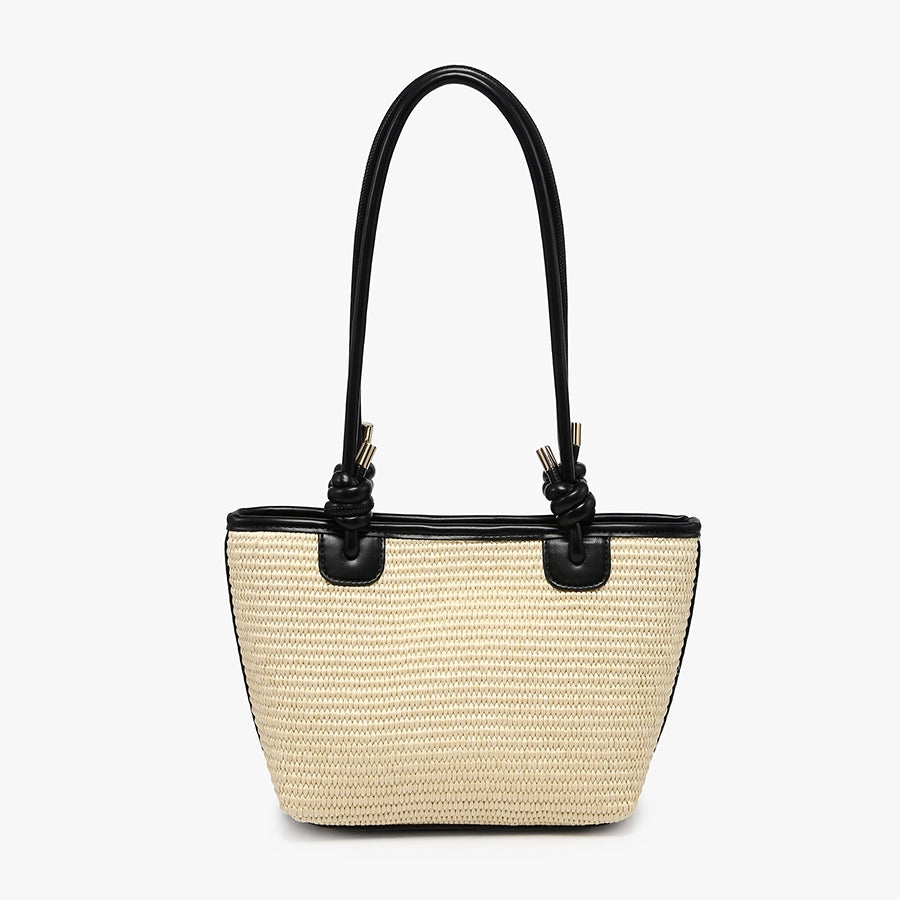 Beige straw handbag with black accents and black shoulder strap close-up
