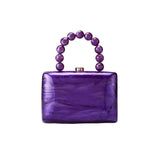Purple handbag with beaded handle on a white background