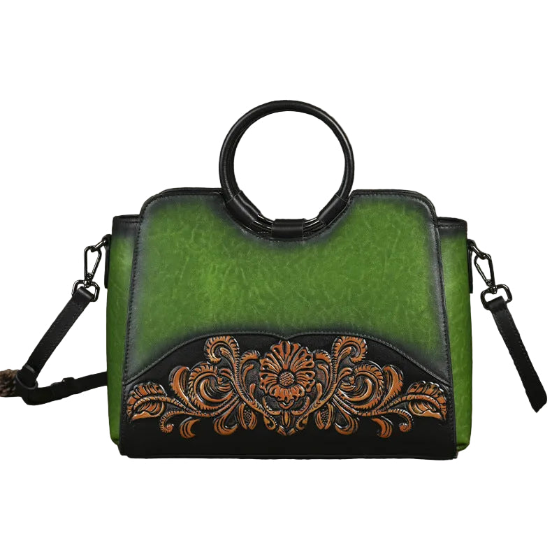 A green and black handbag with a circular top handle and an ornate floral embroidered design on the lower front.
