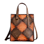 Leather tote bag with patchwork design of dark brown and orange embossed damask patterns, featuring dark brown leather handles and a shoulder strap.