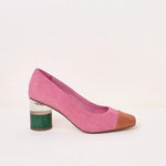 A pink suede pump with a pointed toe in brown leather and a chunky block heel featuring a green textured lower half, shown against a plain off-white background.