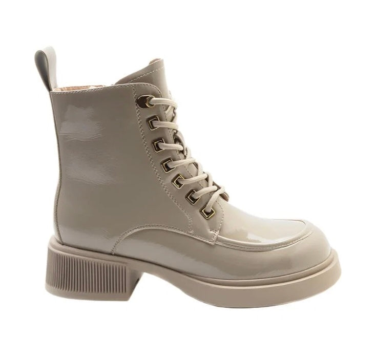 A single light beige patent leather lace-up ankle boot with a chunky ribbed block heel and metal eyelets, shown from a side profile on a white background.