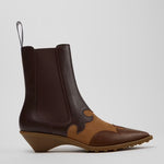 A dark brown and tan leather ankle boot with a wedge heel, elastic side gore, and pull loop, shown from a side profile 