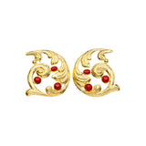 Pair of gold colored earrings with red stones accents on a white background