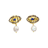 Gold colored eye shaped earrings with blue stones and pearl like accent drops on a white background