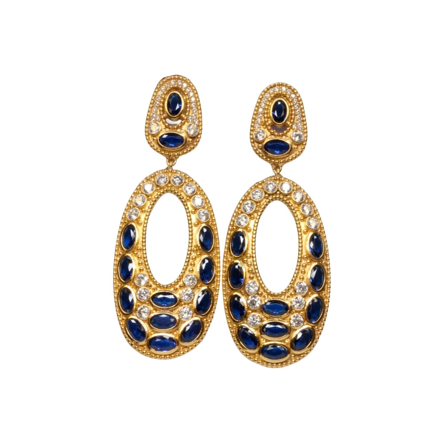 Gold colored earrings with dark blue and white crystal accents on a white background