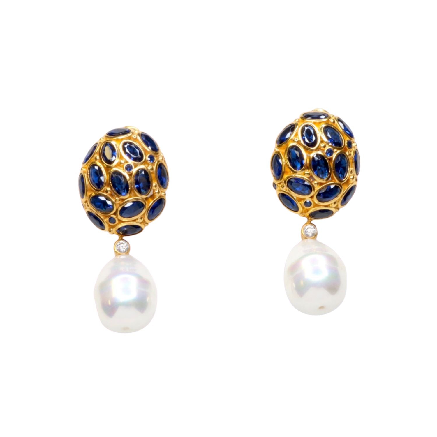 Pair of gold colored earrings with blue crystal and pearl like drop accents on a white background