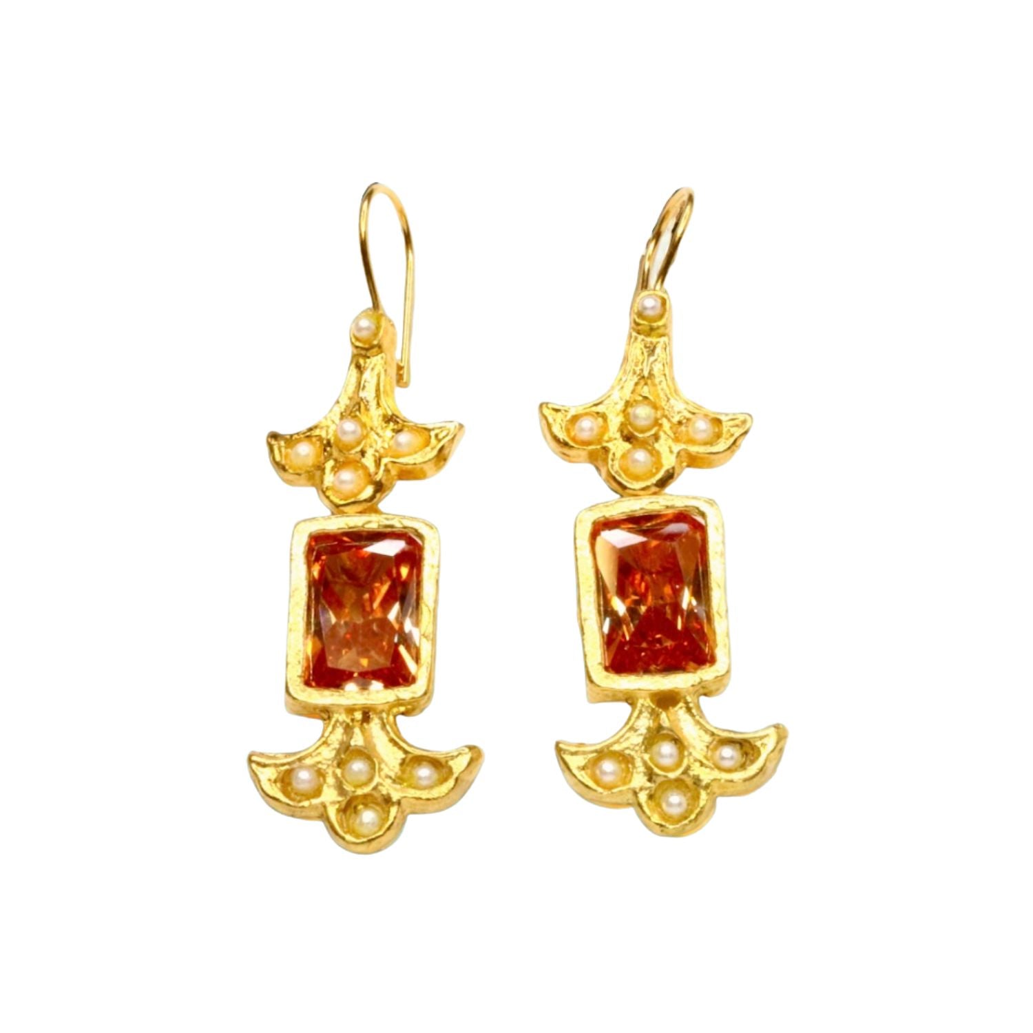 Gold colored earrings with orange stones and pearl like beads on a white background