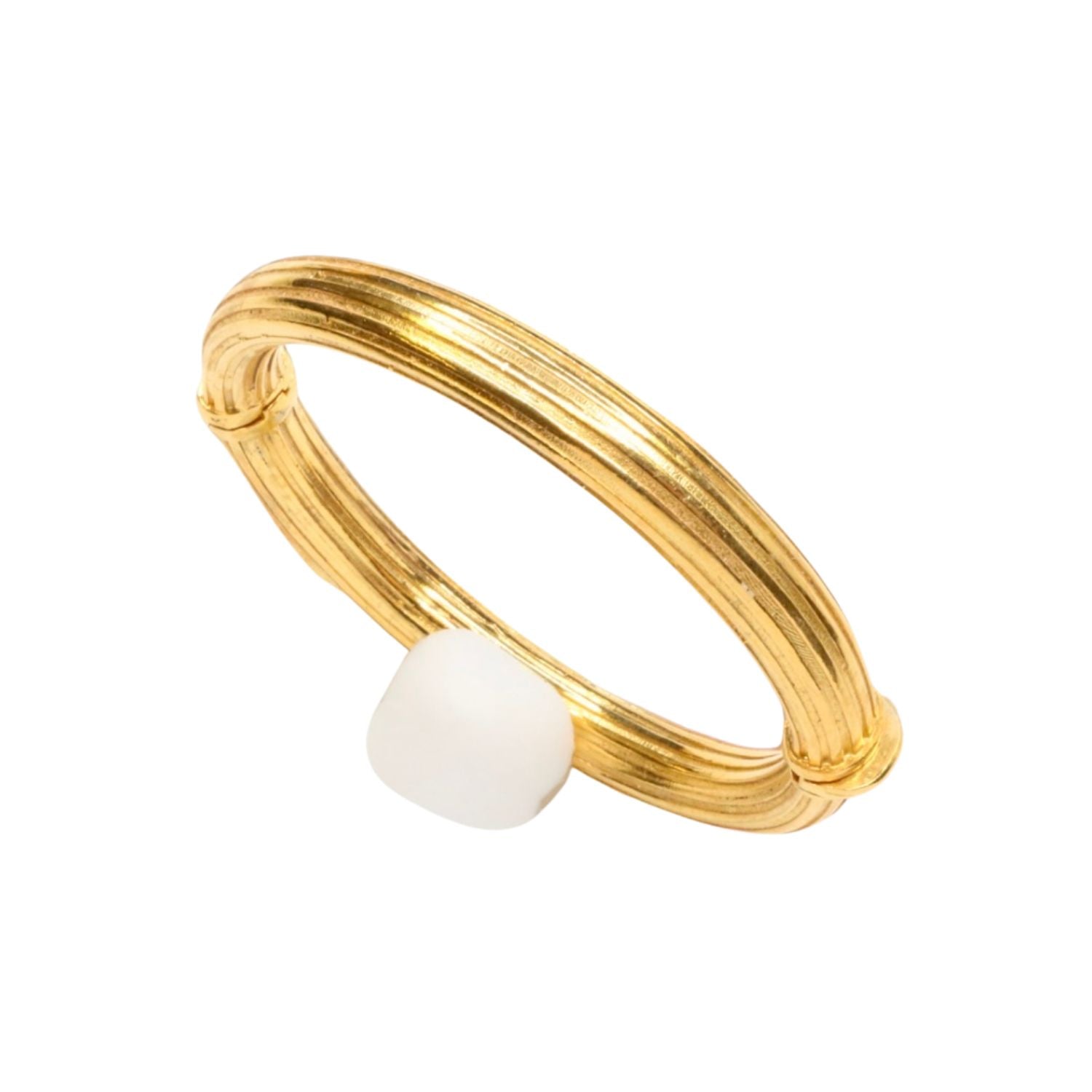 Gold bangle bracelet with a white bead on a white background