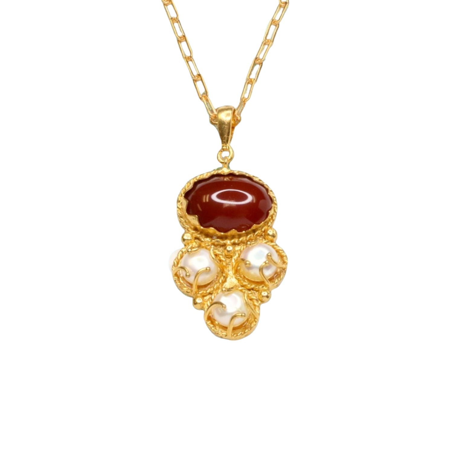 Gold colored necklace with a red stone and pearl-like accents on a gold elongated link chain on a white background