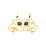 Gold colored snake shaped earrings with blue stones on a white background