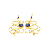 Gold colored snake shaped earrings with blue stones on a white background