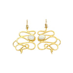 Gold colored snake shaped earrings with white stone accents on a white background
